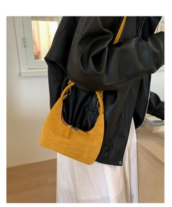 Close-up of bright yellow suede hobo bag with metal buckle and soft leather texture