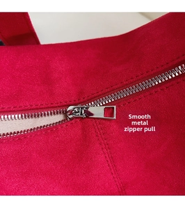 Detail van rood suède materiaal met een zilveren ritstrekker en gladde ritstanden