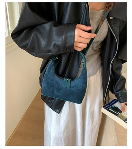 Detail of dark blue suede crescent hobo bag with zip closure and slim handle strap