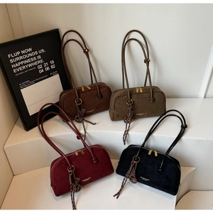 Detailed view of suede shoulder bags in dark brown, olive green, burgundy, and black