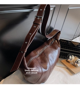 Macro view of dark brown glossy leather shoulder bag with wide strap and silver buckles