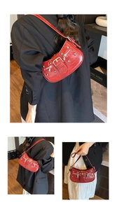 Detail of red punk shoulder bag featuring metallic rivets and decorative zipper straps
