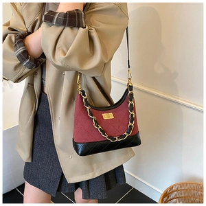 Detail of red and black quilted fabric shoulder bag with gold chain and turn-lock
