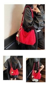 Detail view of large red suede tote bag featuring decorative fringe and ball charms