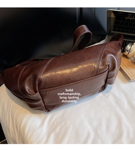 Macro detail of dark brown leather dumpling bag showing stitching and vintage texture