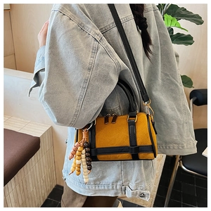 Detail of mustard yellow suede Boston bag with colorful bead tassel and gold hardware