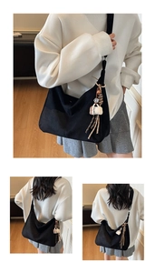 Detailed view of black canvas half-moon tote bag with coffee-themed pendant and tassel