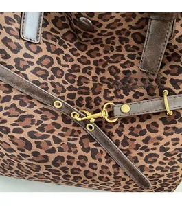 Close-up of leopard print canvas with premium gold hardware and brown leather trim