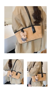 Detail of khaki suede tote bag with black leather straps and a cute dog plush pendant