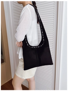 Détail des rivets argentés sur sac hobo en daim noir avec bandoulière large