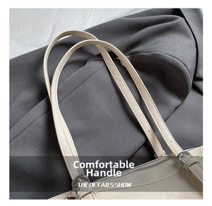 Dettaglio del manico in pelle beige con fibbie argentate e cuciture a doppio filo