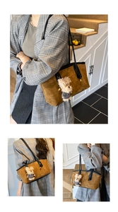 Close-up of vintage brown suede tote bag with black leather straps and cute bear pendant