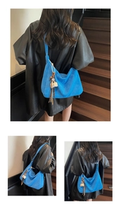 Detail view of electric blue suede tote bag with fringe tassel and decorative charms