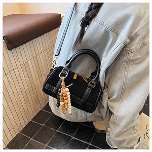Side view of black Boston handbag with wooden bead charm and long leather strap