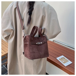 Detail of brown suede bucket bag featuring golden buckle and adjustable shoulder strap