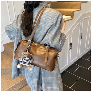 Dettaglio borsa a tracolla vintage in pelle cerata marrone con spalline regolabili e orsetto