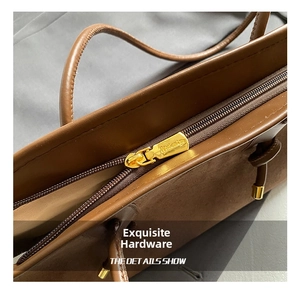 Close-up of golden metal zipper and brown leather texture on a vintage tote bag