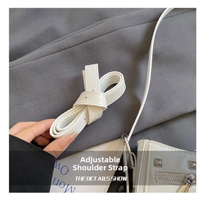 Detail view of white leather adjustable strap with silver square studs and zipper accents