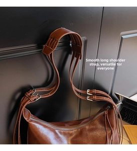 Detail of adjustable shoulder strap and tassel on brown faux leather hobo tote bag