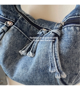Detailed close-up of blue washed denim bag with vintage fringe zipper pulls and tassels