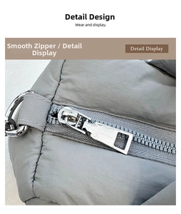 Detail view of the silver metal zipper and D-ring on a grey quilted puffer bag