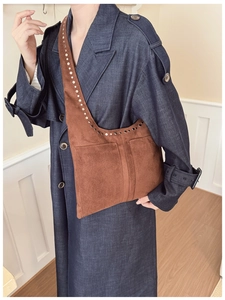 Détail d'un sac cabas en daim marron avec rivets métalliques et deux poches frontales