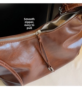 Detail of smooth silver zipper and textured brown leather on large capacity tote bag