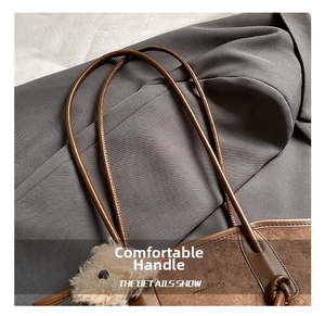 Detail of retro brown suede tote with cylindrical handles and cute bear charm