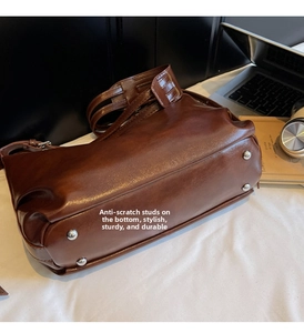 Detailed view of the brown leather tote bag bottom with four silver protective studs