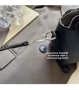 Makroaufnahme glänzender Silberbeschläge und D-Ring an schwarzer Lederhandtasche