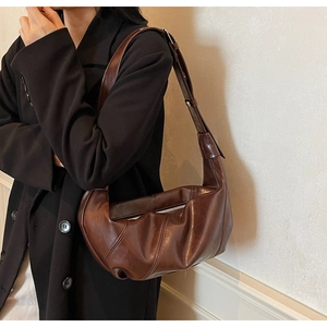 Detail of coffee brown leather shoulder bag with pleated stitching and metal zipper