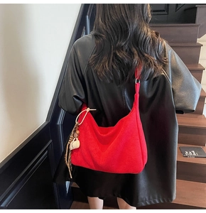 Detail of red matte tote bag with a coffee cup charm on a model in an indoor setting