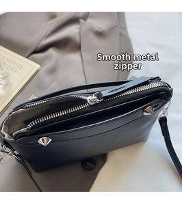 Details vom silbernen Reißverschluss und Metallnieten an der schwarzen Lederhandtasche