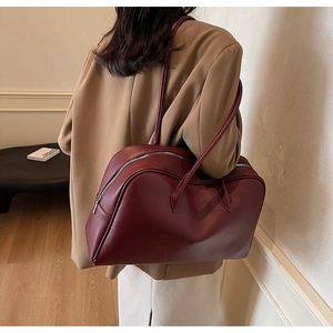 Dettaglio della borsa tote bordeaux con texture litchi portata da una modella in tailleur