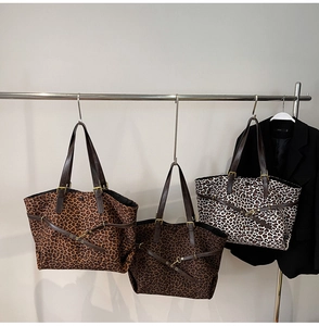Detail of leopard print tote bag featuring leather straps and brass metal hardware