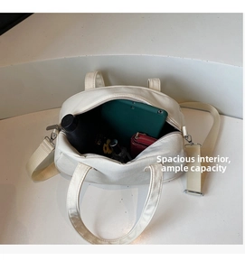 Spacious interior of a cream canvas shell bag holding a tablet, bottle, and wallet
