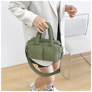 Detail of green quilted puffer tote bag showing padded handles and detachable strap