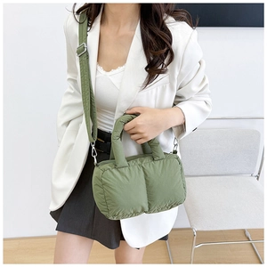 Model wearing a grass green quilted puffer tote bag with a matching wide shoulder strap