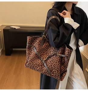 Detail of leopard print tote bag with brown leather straps and gold metal buckle