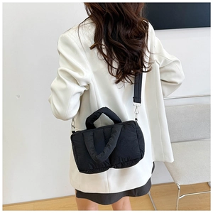 Detail of a black quilted puffer bag with adjustable shoulder strap and silver hardware