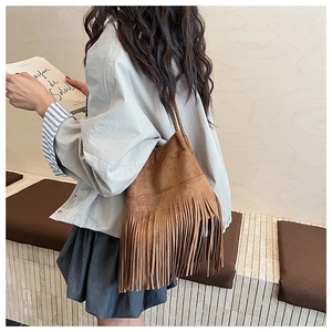 Detalle de bolso de gamuza marrón oscuro con flecos densos y estilo bohemio chic