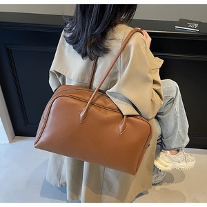 Dettaglio borsa tote in pelle marrone motivo litchi con manici lunghi e chiusura a cerniera