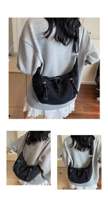 Détail du sac croissant en denim noir délavé avec plusieurs poches zippées et pompons