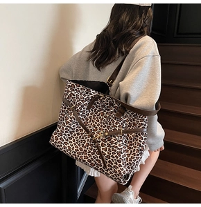 Detail of leopard print tote bag with adjustable brown strap shown on a model