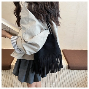 Detalle del bolso de ante negro con flecos largos mostrado en una toma de estilo de vida