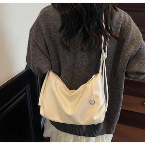 Detail of cream white faux leather tote bag with knotted strap and silver ring accent