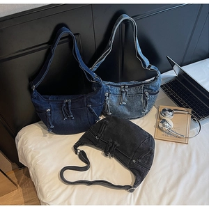 Three washed denim dumpling bags in blue and grey displayed with trendy lifestyle props