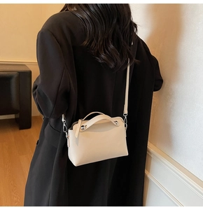 Modische beige Boston-Tasche mit silbernen Nieten getragen über einem schwarzen Blazer