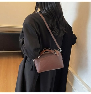 Details der braunen Lederhandtasche mit Metallnieten an einem Mantel-Model