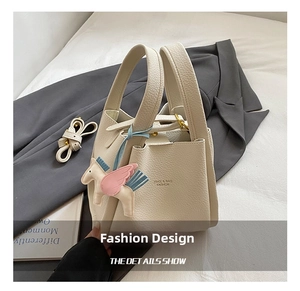 Detail shot of the beige leather bucket bag featuring a cute pegasus charm and handle.